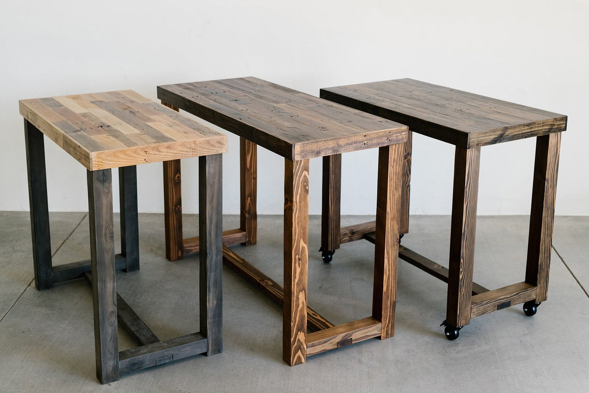 Reclaimed wood bar height tables in three finish colors — natural, medium, and dark — handcrafted by Kase Custom with sturdy u-shape leg bases.