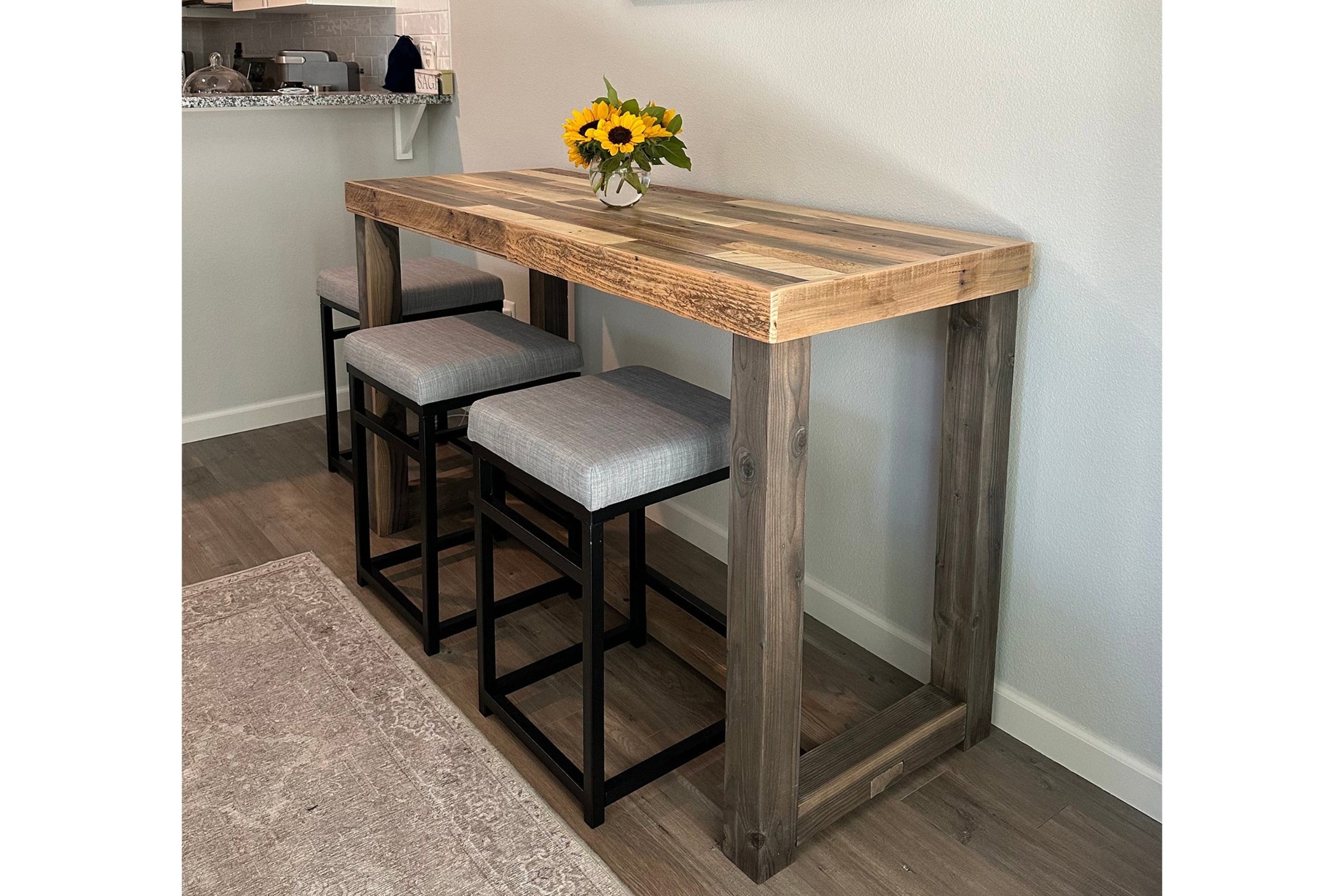 Handcrafted in Arizona, this reclaimed wood bar-height table showcases enduring quality and sustainable craftsmanship. Paired with three cushioned stools with black steel frames, it's ideal as a narrow kitchen island or restaurant table.