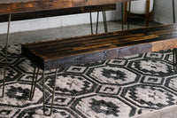 Handcrafted in Arizona, this reclaimed wood narrow bench features sleek steel hairpin legs and rests on a geometric black-and-white rug. Ideal as a kitchen island seat or restaurant table accent, it fuses sustainability with lasting quality.