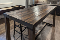 This handcrafted Sequoia bar-height table, made from sustainably sourced reclaimed wood with a rich dark finish, anchors a modern kitchen. Surrounded by high chairs, this durable reclaimed wood furniture exudes enduring quality.