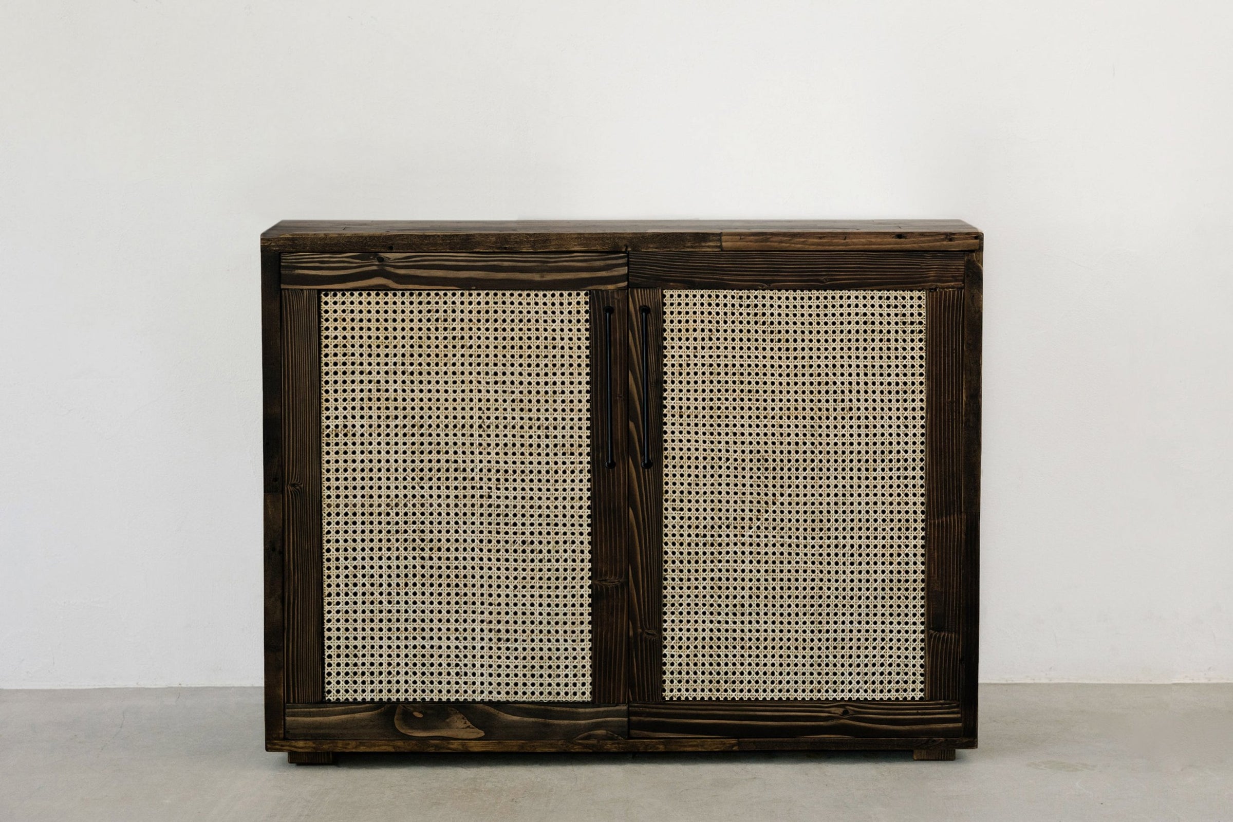 Expertly crafted sideboard features sliding doors with handwoven cane panels and a dark reclaimed wood frame. This durable, narrow piece adds sustainable elegance to any dining or restaurant space.