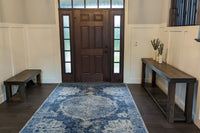 A handcrafted reclaimed wood console table, sustainably sourced and expertly crafted in Arizona, anchors the bright entryway with enduring quality. Paired with a blue rug and wooden bench, this narrow reclaimed wood furniture piece offers timeless appeal.