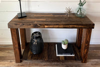 Handcrafted in Arizona from reclaimed wood, this narrow console table highlights timeless craftsmanship. Its sturdy design displays a black lamp, metal sculpture, and glass vase; the shelf below holds curated décor accents.