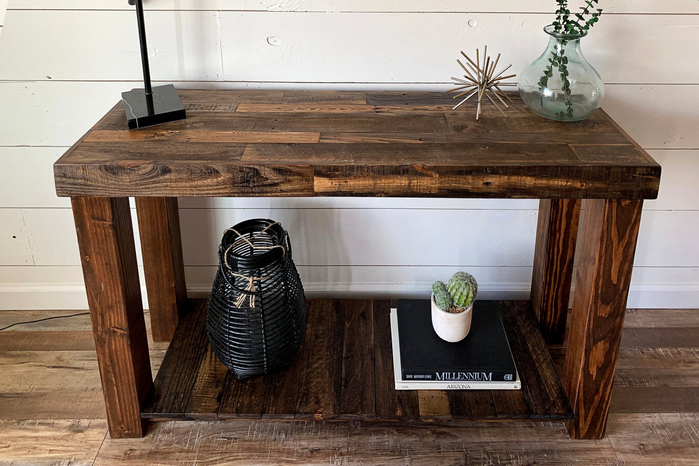 Handcrafted in Arizona from reclaimed wood, this narrow console table highlights timeless craftsmanship. Its sturdy design displays a black lamp, metal sculpture, and glass vase; the shelf below holds curated décor accents.
