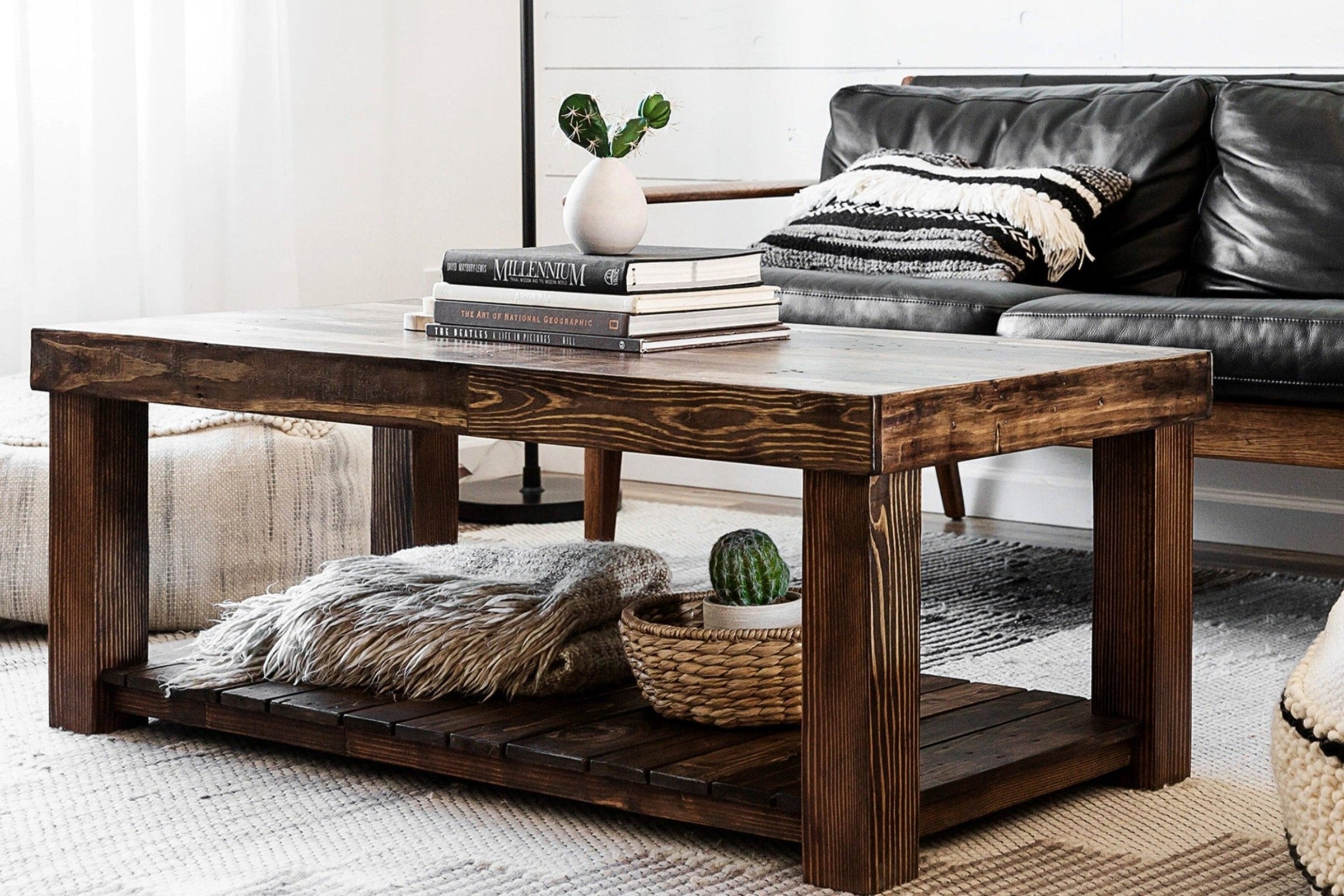 Experience lasting quality with this handcrafted reclaimed wood coffee table—perfect as a narrow table or centerpiece. Set before a black leather sofa, it features a lower shelf for decor and blankets, showcasing artisanal craftsmanship.