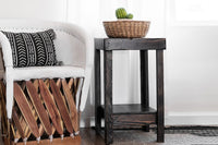 A white armchair with black and white cushions pairs beautifully with a handcrafted solid reclaimed wood side table, perfect as a narrow bar table or accent piece. A woven basket with green gourds adds artisanal charm.