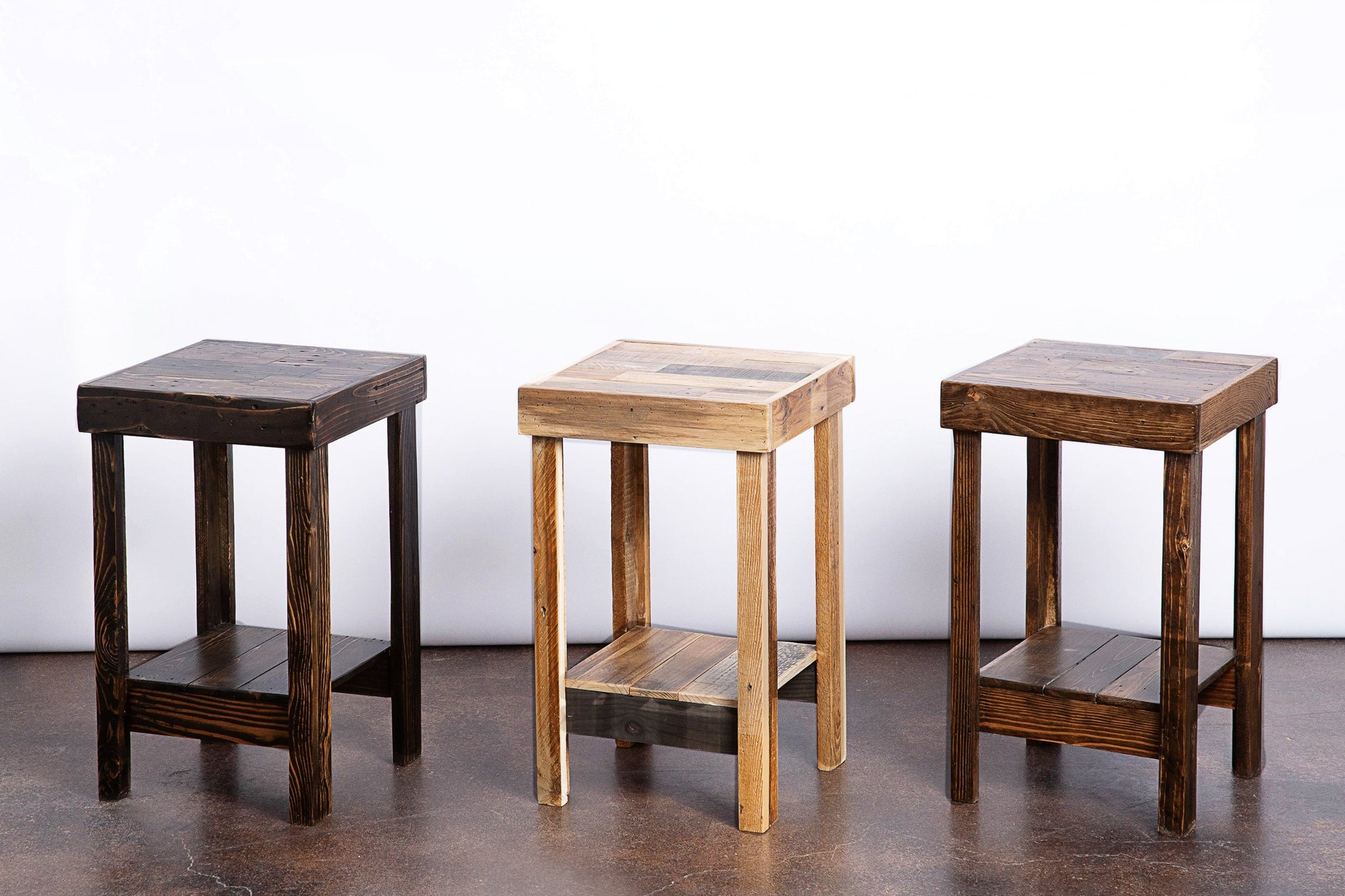 Beautifully crafted in Arizona, these narrow bar-height tables showcase reclaimed wood tops and lower shelves in rich dark brown, light natural, and medium brown finishes—perfect as kitchen islands or restaurant tables.