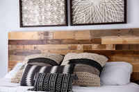 Experience enduring comfort with this handcrafted bed featuring a rustic reclaimed wood headboard, crisp white bedding, and artisan-textured pillows. Above, geometric art prints complement the refined style of sustainable furniture design.