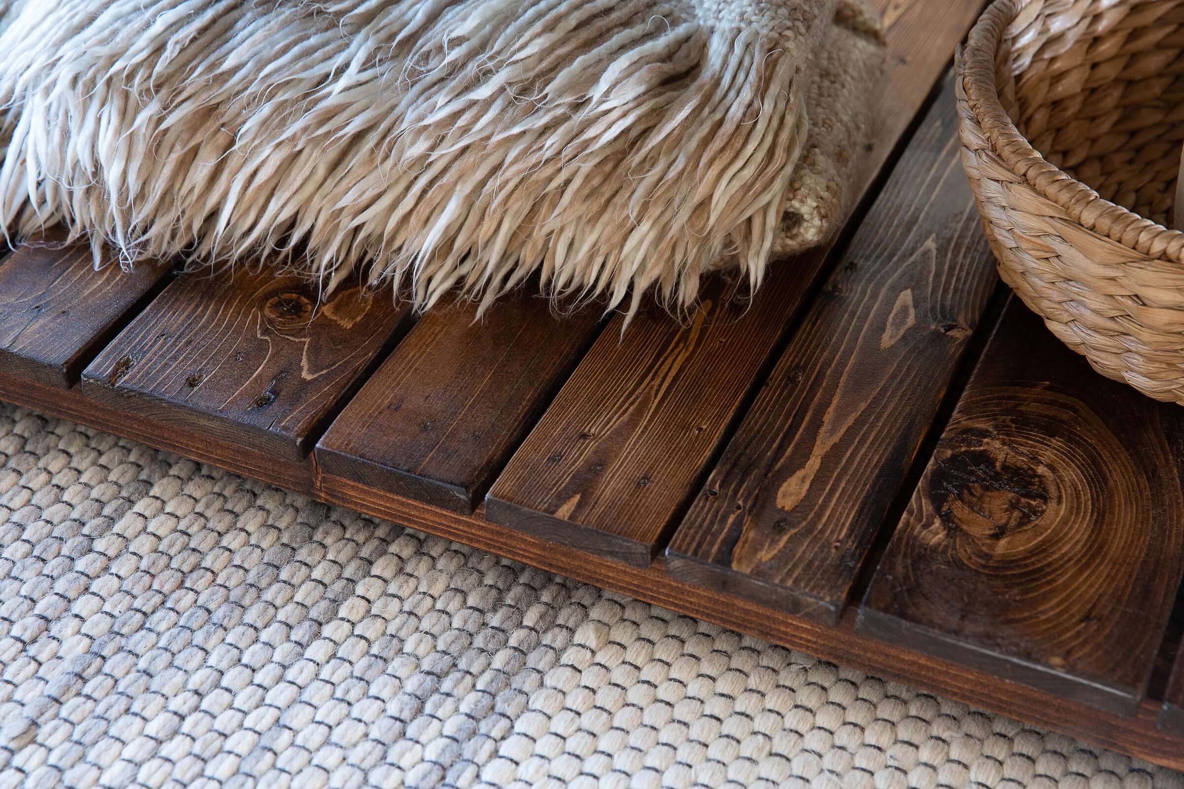 Experience the inviting comfort of a handcrafted reclaimed wood bench, topped with a plush beige cushion and paired with a woven basket. This Arizona-made piece adds cozy charm to any space—perfect as sustainable reclaimed wood furniture.