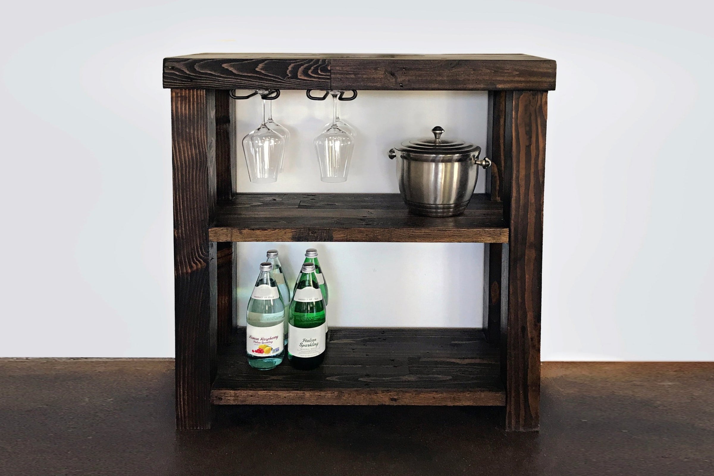 Handcrafted in Arizona, this artisanal bar cart features reclaimed wood and a sturdy steel base. Bar-height table design with hanging wine glasses, ice bucket, and storage for bottles—perfect for home or restaurant spaces.