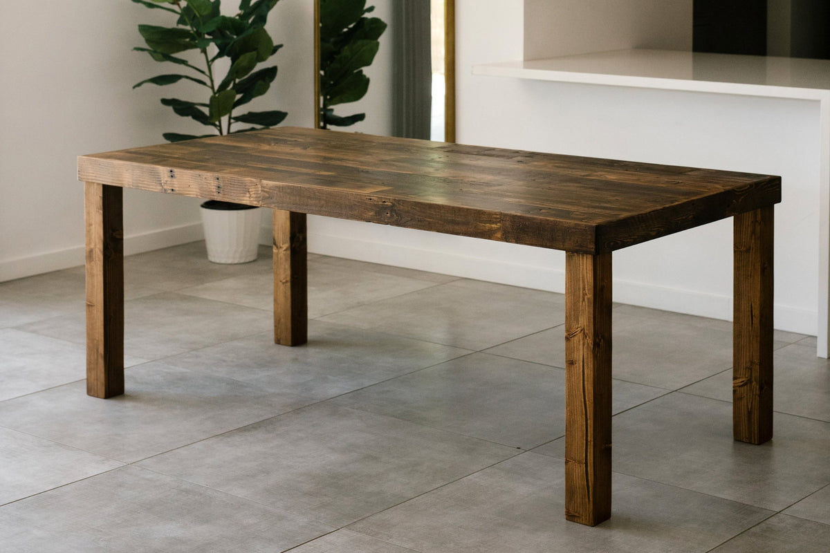 Discover timeless craftsmanship with this handcrafted dining table, built in Arizona from reclaimed wood and finished in a rich dark tone. Ideal as a narrow dining table or kitchen island for modern, minimalist spaces. A lush potted plant adds warmth.