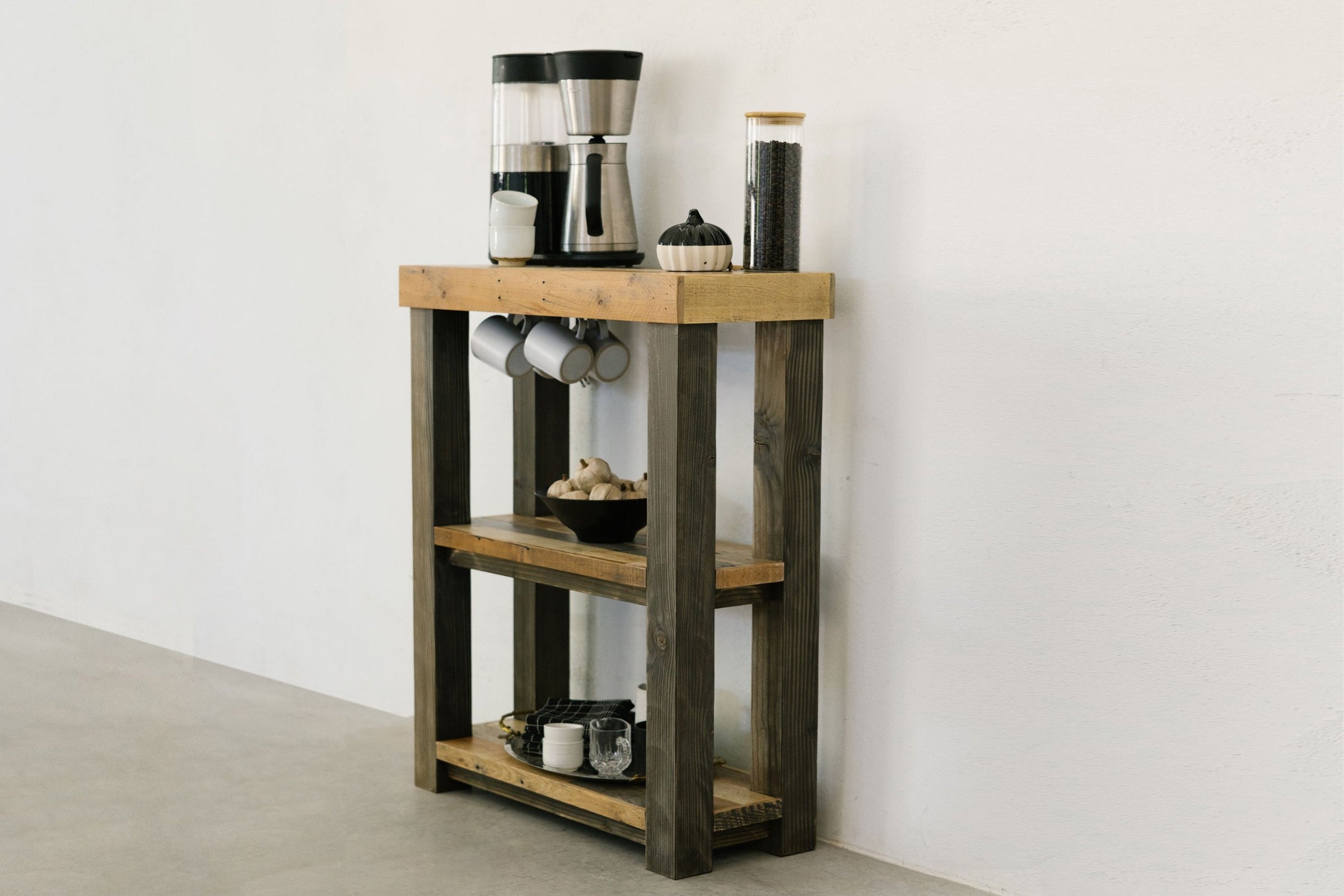 This inviting coffee station showcases artisan craftsmanship, with a coffee maker and accessories arranged atop a handcrafted reclaimed wood bar-height table. Built in Arizona, this durable reclaimed wood furniture adds warmth and enduring style.