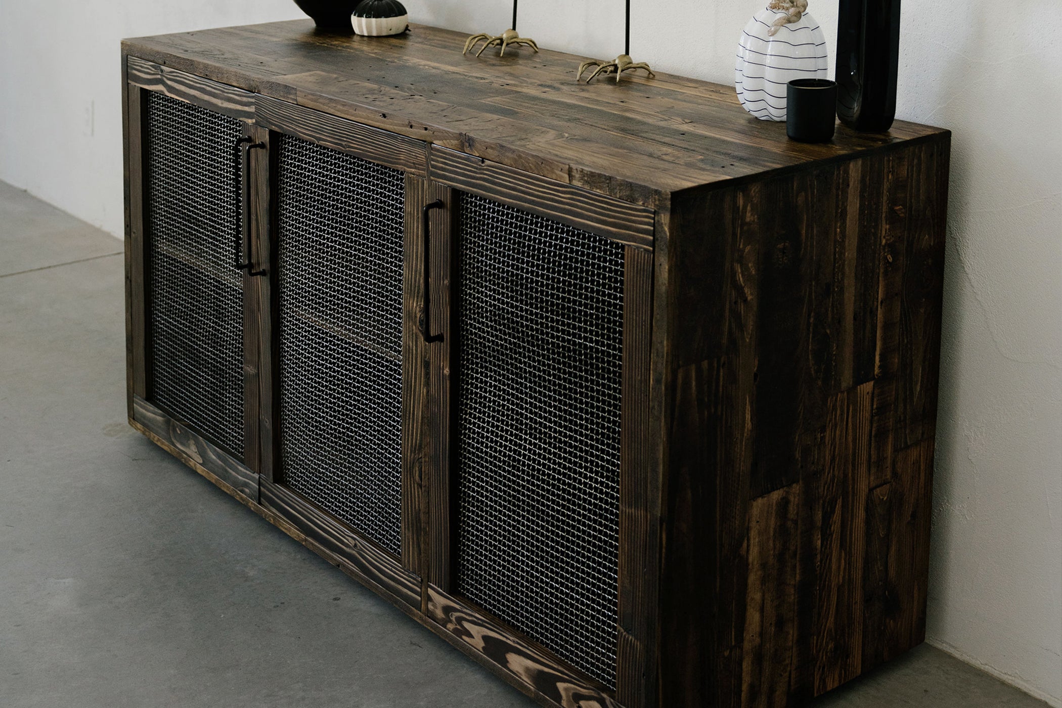 This handcrafted reclaimed wood sideboard features mesh panel doors and sleek black handles, beautifully showcasing sustainable craftsmanship. Ideal as a narrow bar table or counter-height reclaimed wood furniture centerpiece.