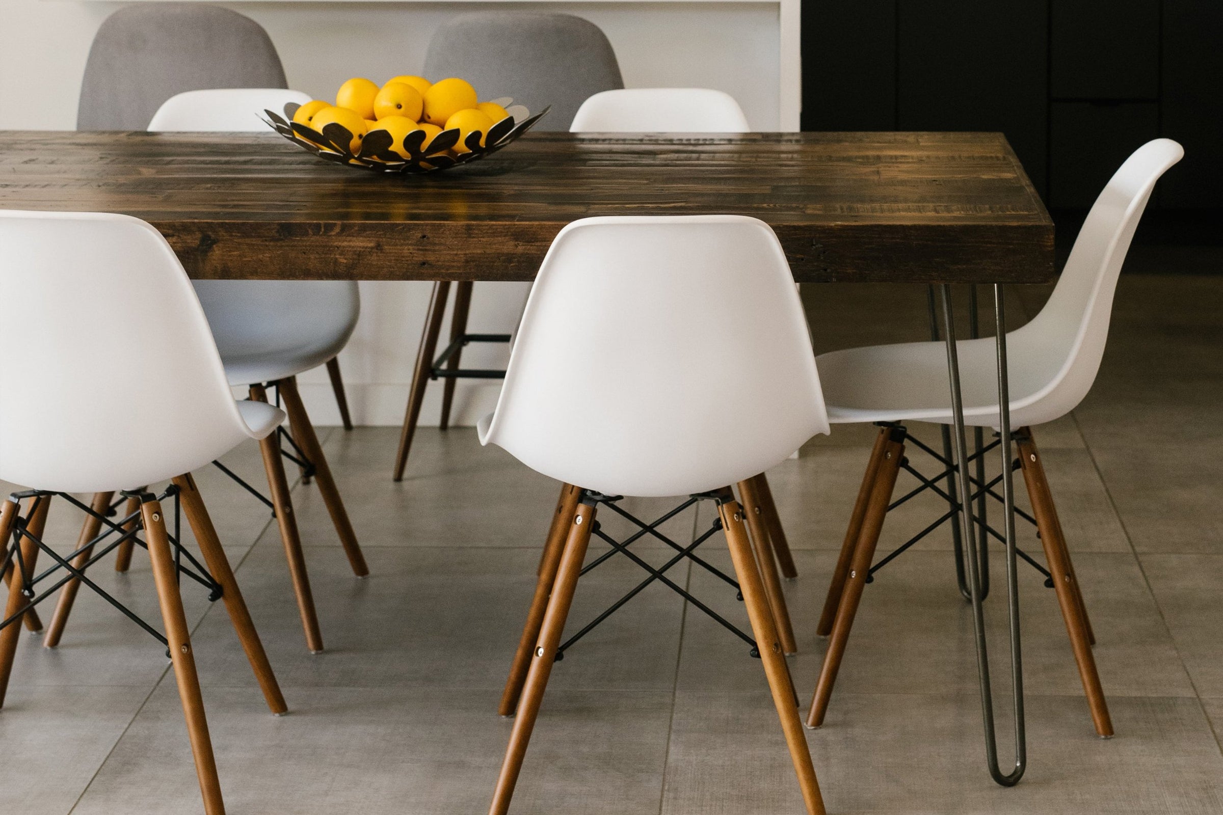Experience enduring quality with this handcrafted reclaimed wood dining table, paired with sleek white and gray chairs. Perfect for modern dining or restaurant spaces, it features artisanal detail and eco-conscious materials.