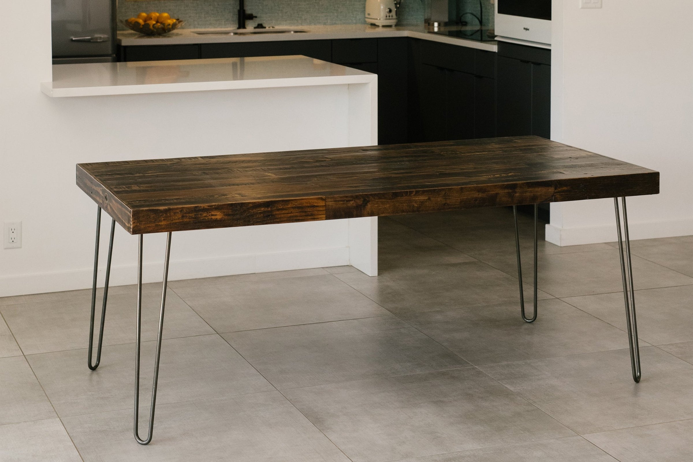 This handcrafted dining table features a rich, reclaimed wood top and sleek steel hairpin legs. Perfect as a narrow bar-height table or kitchen island, it brings enduring quality and sustainable style to modern spaces.