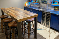 Elevate your space with a handcrafted Sequoia bar-height table and four matching stools, expertly built from reclaimed wood in Arizona. This durable piece anchors a modern home bar with blue cabinets, marble counters, and curated shelving.