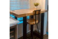 This handcrafted Gunnison bar-height table features a reclaimed wood top and durable industrial steel legs, paired with a matching bar stool. Perfect as a kitchen island or restaurant table, bathed in warm natural light.