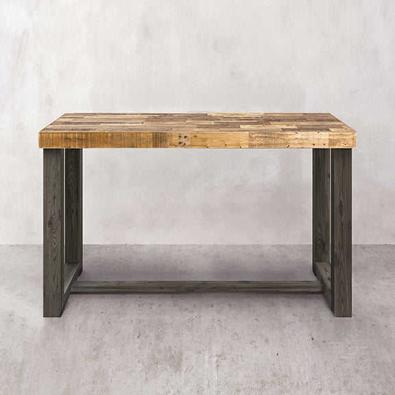 Bar-height dining table handcrafted in Arizona from reclaimed wood with a thick, light-colored rectangular top and dark steel legs; ideal for modern café, minimalist space, or historic home. Set against a light gray textured wall and floor.