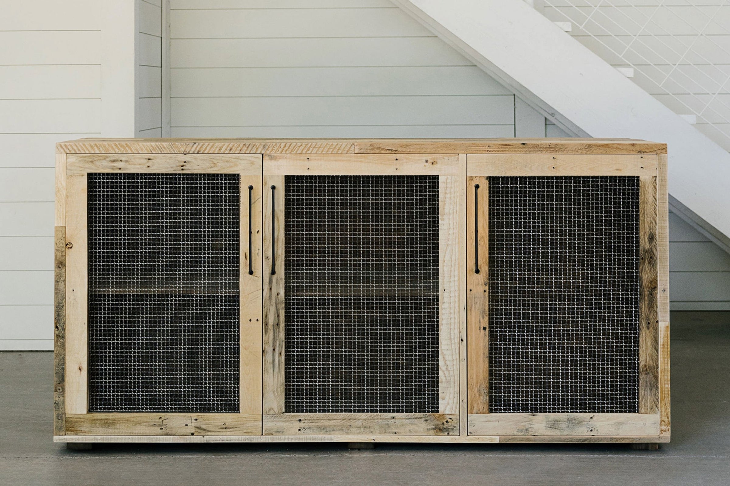 Handcrafted in Arizona, this reclaimed wood sideboard features four doors with black mesh panels and sleek vertical handles. Ideal as a narrow bar-height table or as reclaimed wood furniture for kitchens and dining spaces.