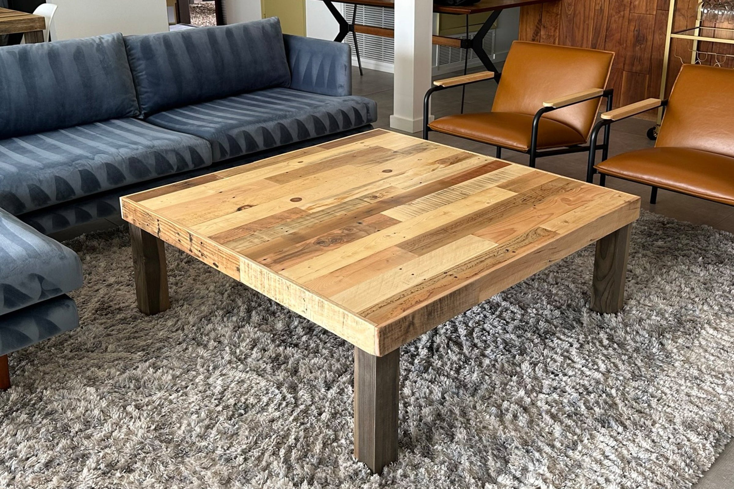 This handcrafted reclaimed wood coffee table, featuring a mixed plank top and robust dark legs, showcases artisan quality. Perfect as a living room centerpiece for sustainable décor and enduring style, on trend with reclaimed wood furniture.