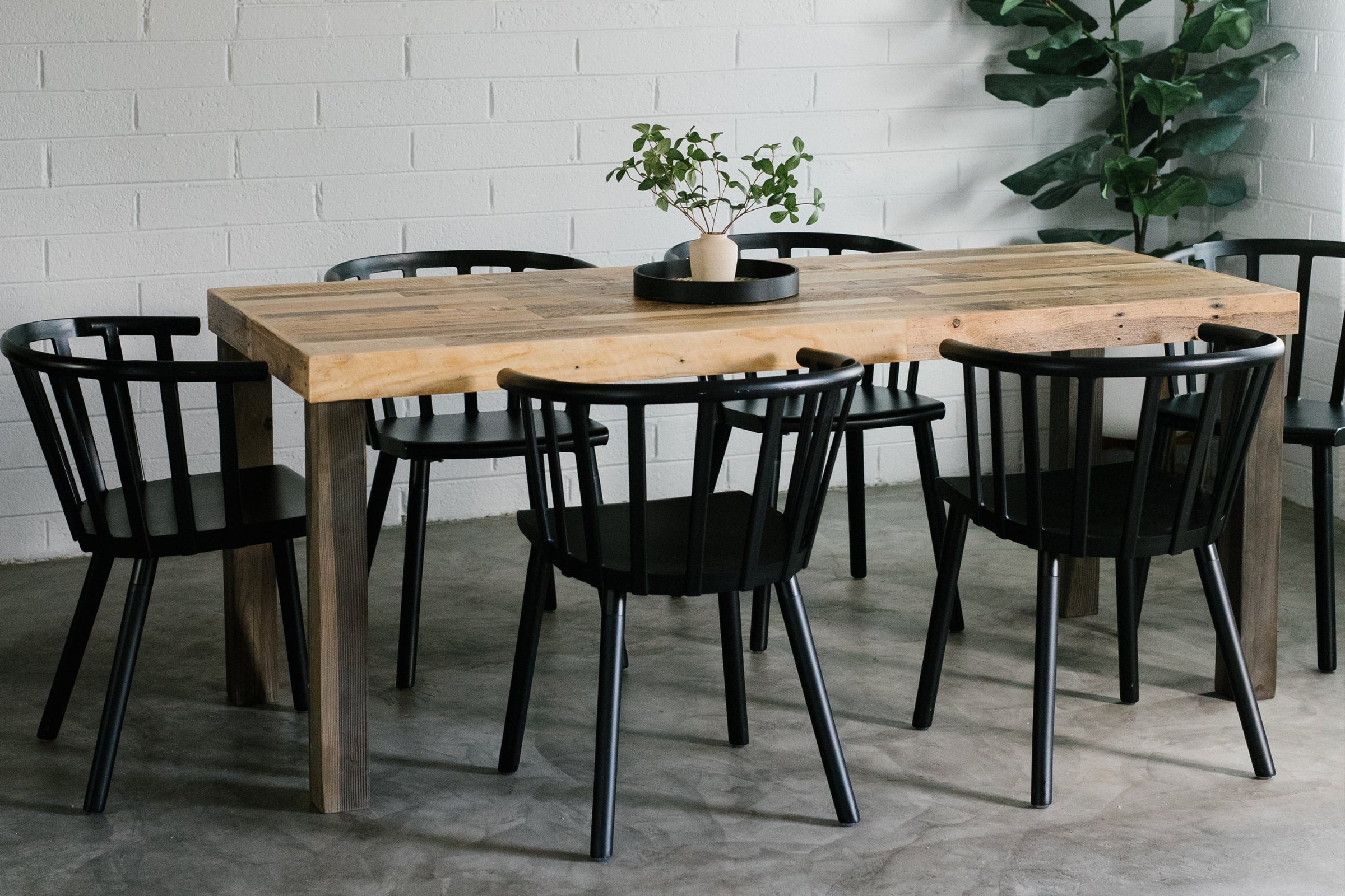 This handcrafted dining table, made from sustainable reclaimed wood and paired with six sleek black chairs, brings enduring quality to your space. Ideal as a kitchen island or restaurant table, it’s showcased in a bright modern room.