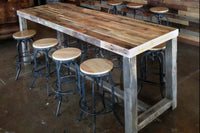 Handcrafted in Arizona, this bar-height reclaimed wood table features a sturdy steel base and is paired with durable high stools. Ideal as a kitchen island, restaurant table, or narrow dining table. Industrial charm endures.
