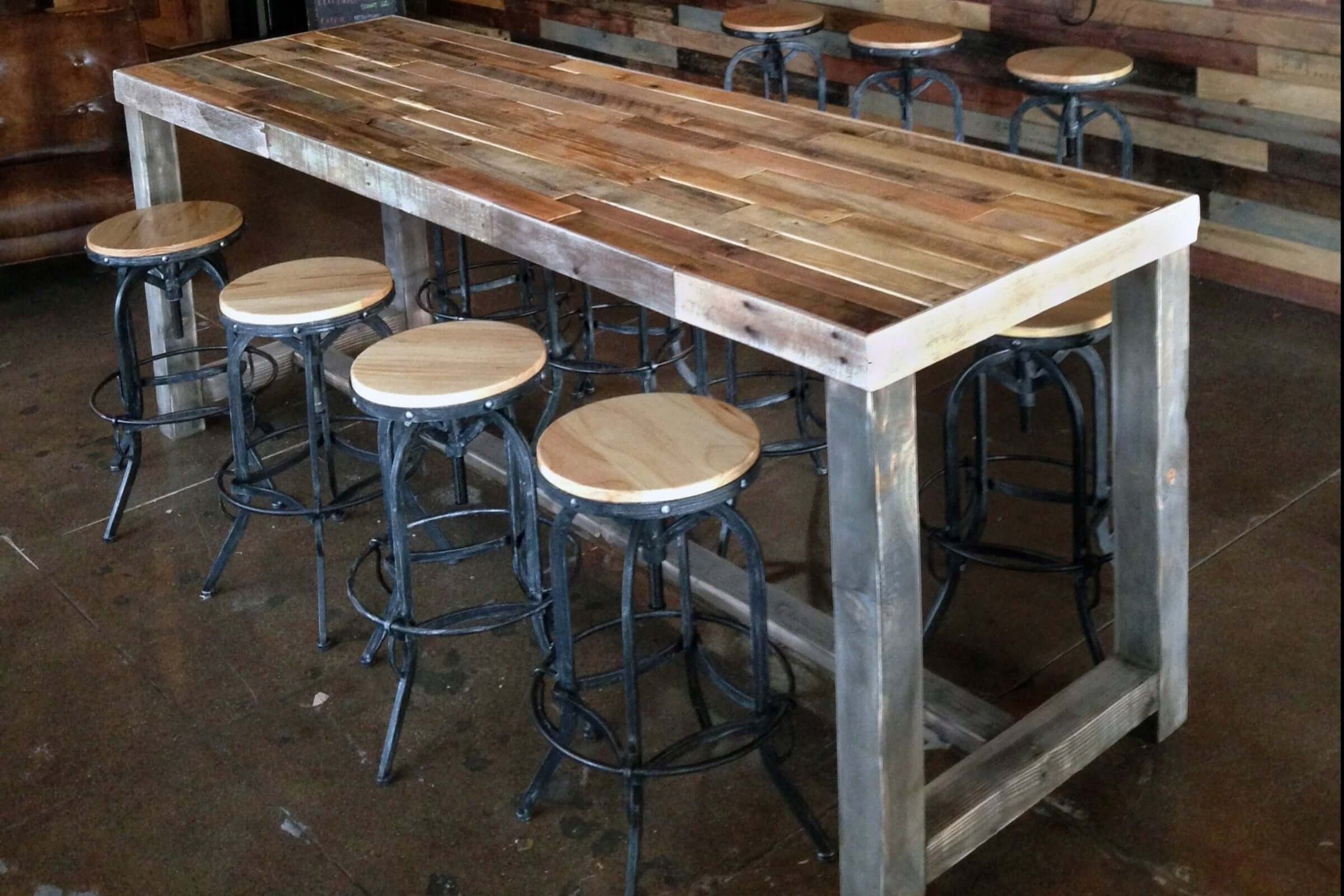 Handcrafted in Arizona, this bar-height reclaimed wood table features a sturdy steel base and is paired with durable high stools. Ideal as a kitchen island, restaurant table, or narrow dining table. Industrial charm endures.