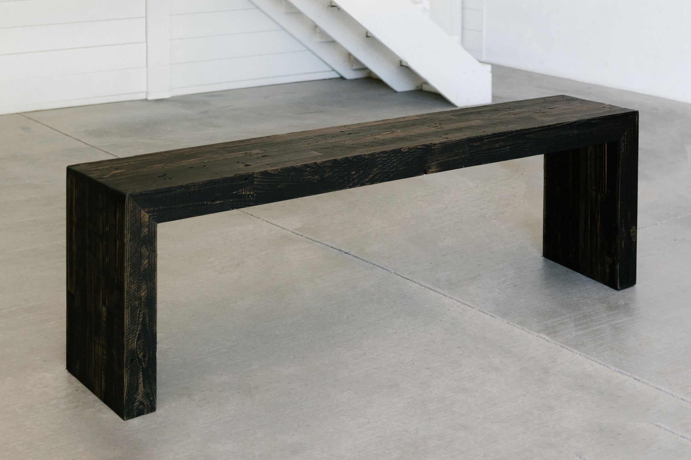 This handcrafted reclaimed wood bench showcases enduring quality and refined design, perfect as a narrow entryway table or restaurant bench. Its sustainable black finish pairs beautifully with minimalist spaces.