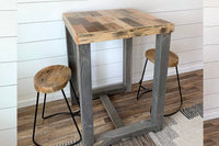 This handcrafted reclaimed wood bar-height table, paired with two matching stools featuring round seats and sturdy metal legs, showcases enduring quality—ideal as a narrow kitchen island or rustic dining table.