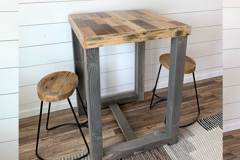 This handcrafted reclaimed wood bar-height table, paired with two matching stools featuring round seats and sturdy metal legs, showcases enduring quality—ideal as a narrow kitchen island or rustic dining table.