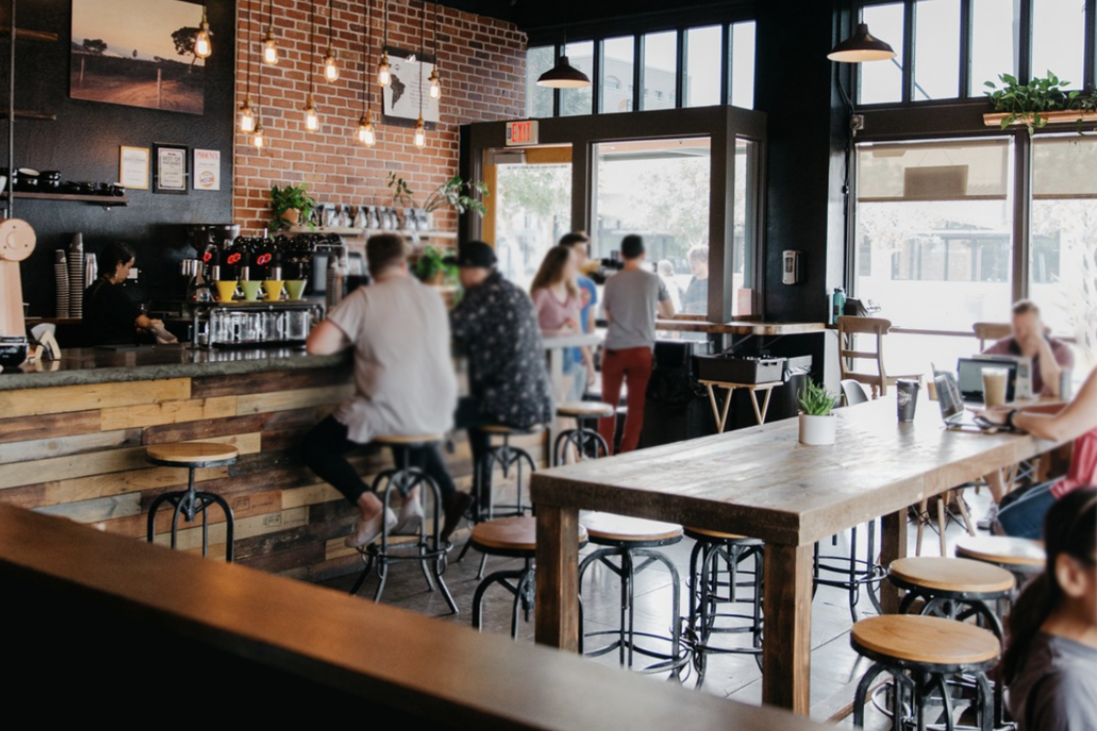 A custom wood bar height table sits in the middle of a busy coffee shop in Chandler, Arizona. 