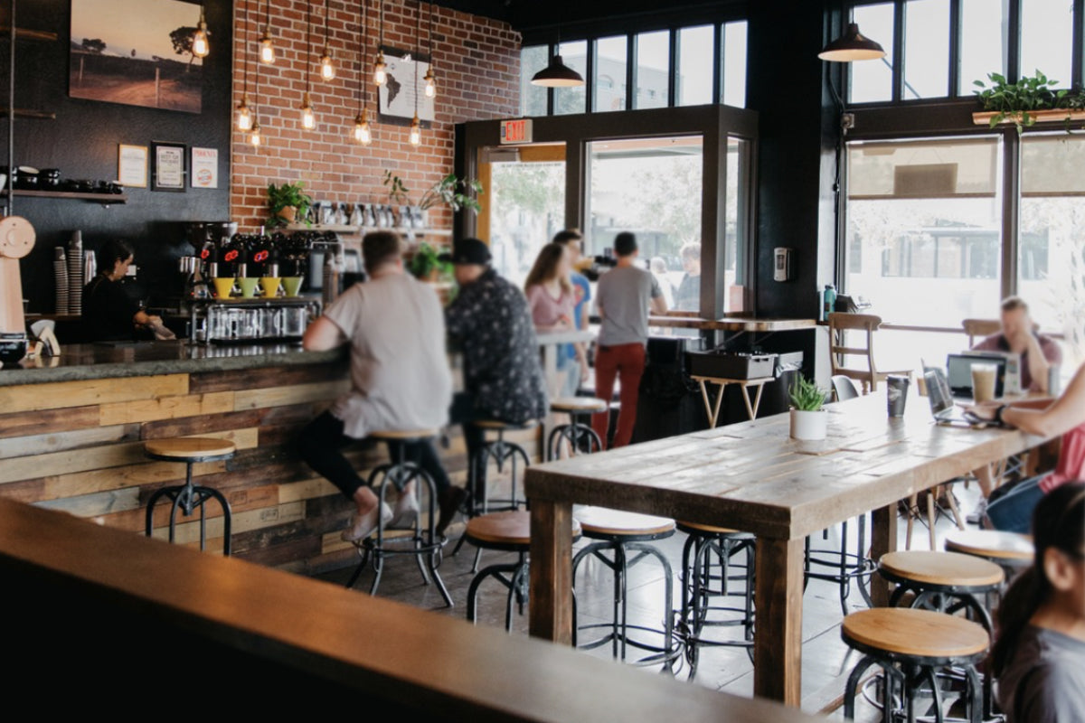 A custom wood bar height table sits in the middle of a busy coffee shop in Chandler, Arizona. 