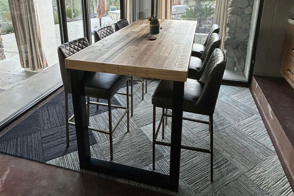 Custom bar height wood table with steel legs and six stools in a modern dining space