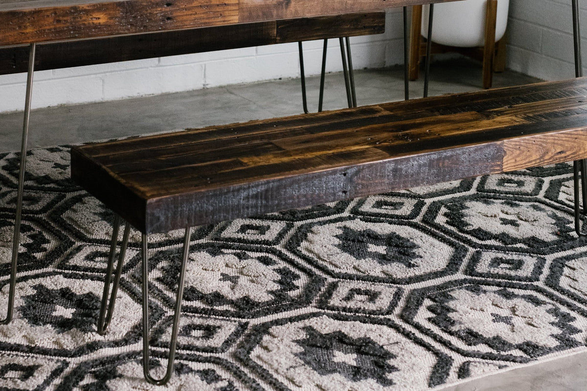 Handcrafted in Arizona, this reclaimed wood narrow bench features sleek steel hairpin legs and rests on a geometric black-and-white rug. Ideal as a kitchen island seat or restaurant table accent, it fuses sustainability with lasting quality.