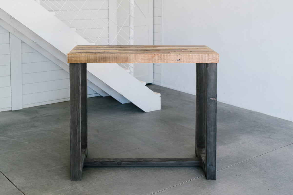 A handcrafted, minimalist Sequoia bar-height table features a thick, light reclaimed wood top and dark steel legs. Made in Arizona with sustainable materials, this reclaimed wood furniture piece exudes enduring quality.