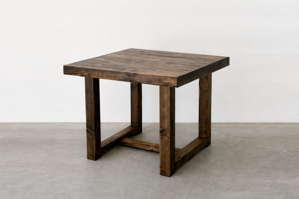 This handcrafted, square dining table features a dark reclaimed wood finish and sturdy straight legs, highlighting visible grain for timeless appeal. Expertly made in Arizona.