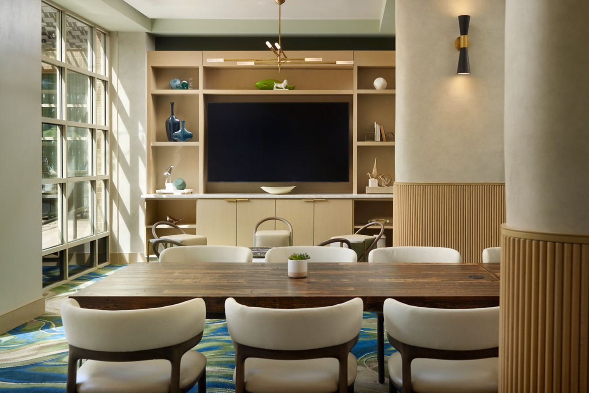 Bright, modern meeting room featuring a handcrafted reclaimed wood conference table—expertly made in Arizona—surrounded by white chairs. Natural light fills the space, accenting sustainable decor and a bar-height table with a steel base.