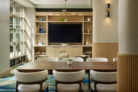 Bright, modern meeting room featuring a handcrafted reclaimed wood conference table—expertly made in Arizona—surrounded by white chairs. Natural light fills the space, accenting sustainable decor and a bar-height table with a steel base.