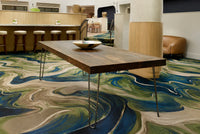 A contemporary space featuring a handcrafted Arizona reclaimed wood bar-height table with sleek hairpin steel legs. Styled with a decorative bowl, bar stools, and artisanal furniture, on a vibrant patterned carpet.