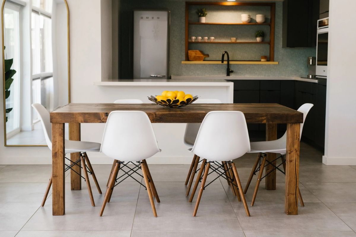 A custom reclaimed wood wood dining table in a medium brown finish in a modern, open concept home with white seating.