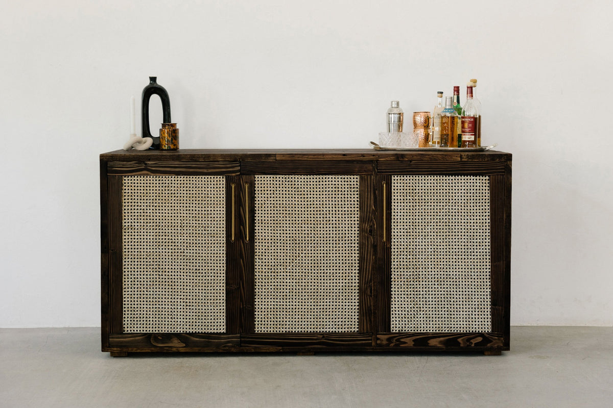 This handcrafted dark wood sideboard features woven rattan panels. Timeless, sustainable style.
