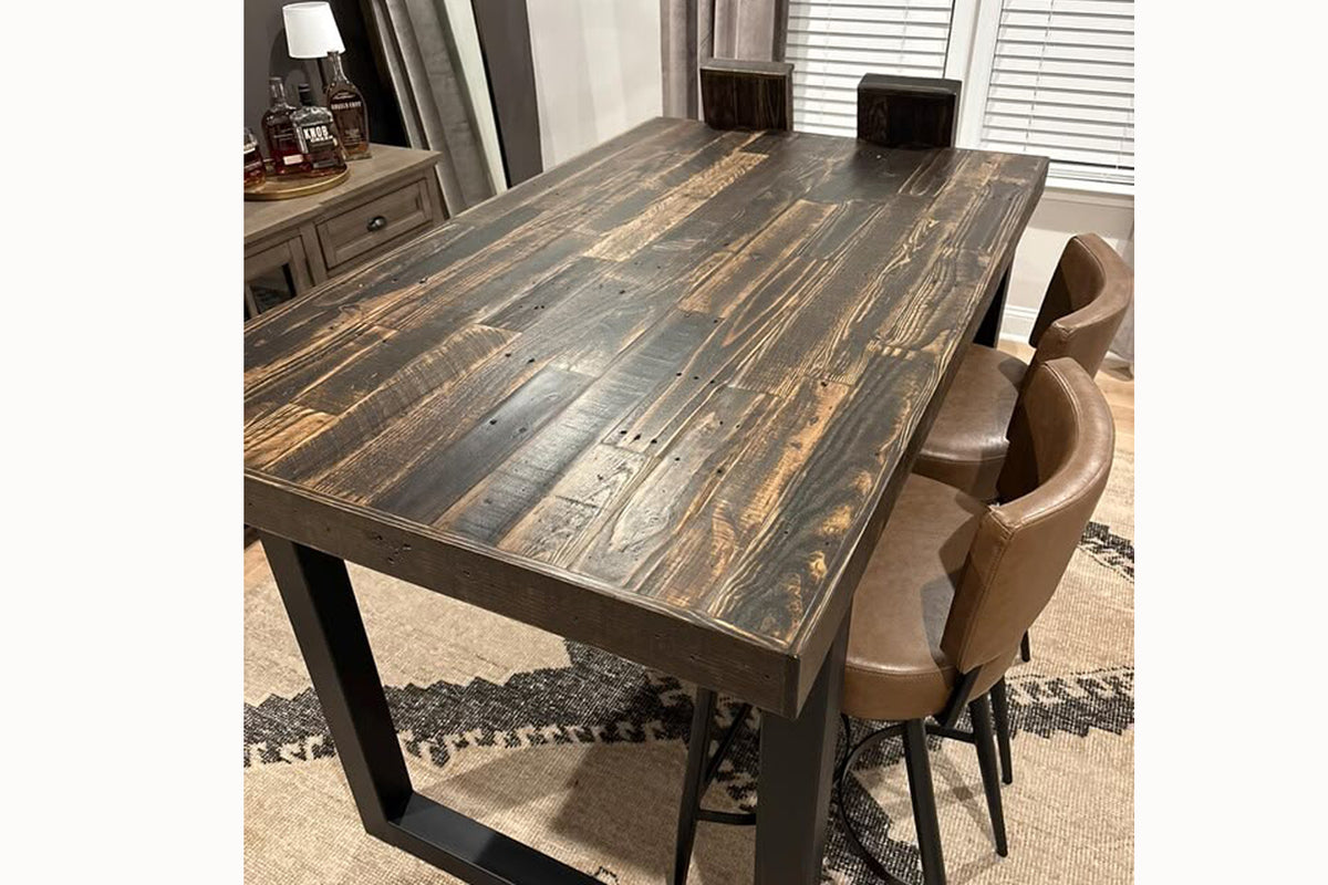 This handcrafted reclaimed wood dining table features a dark, distressed finish, paired with four brown leather chairs. Perfect as a restaurant or kitchen dining table, it offers enduring quality and sustainable craftsmanship.
