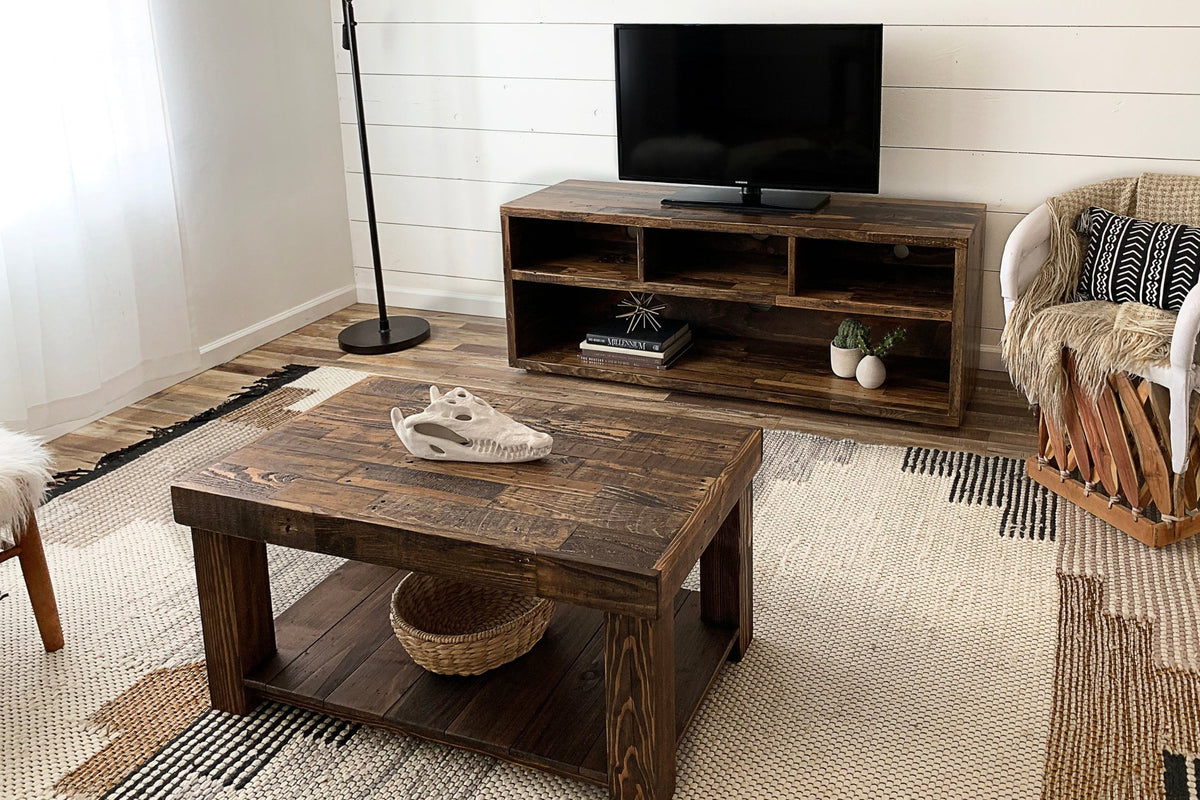 An inviting living room with a handcrafted reclaimed wood TV stand and media console, paired with a woven chair and geometric rug. Made in Arizona.
