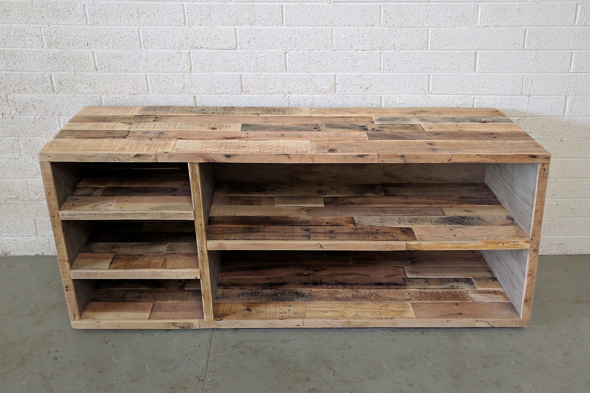 Experience timeless craftsmanship with this handcrafted reclaimed wood storage cabinet, featuring open shelves and set against a white brick wall. 