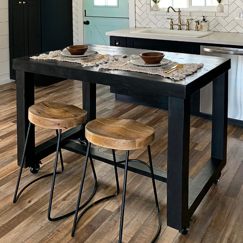 Handcrafted in Arizona, this reclaimed wood kitchen island doubles as a sleek bar-height table, paired with two wooden barstools. Sustainable craftsmanship and enduring quality shine in this warm farmhouse-inspired dining space.