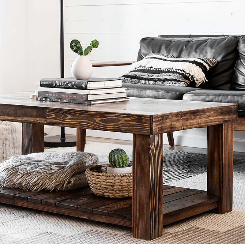 Provincial brown reclaimed wood coffee table in front of black sofa