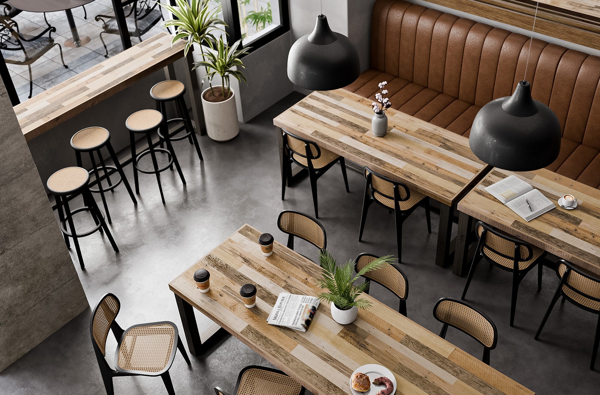 A sunlit cafe features handcrafted reclaimed wood dining tables paired with sleek black chairs and a brown cushioned bench. Hanging black lamps, potted plants, coffee cups, and pastries complete this inviting restaurant setting.