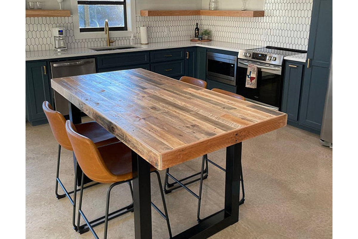 A welcoming kitchen showcases dark blue cabinets and a handcrafted kitchen island featuring a reclaimed wood top and industrial steel base. Paired with bar-height leather chairs, open shelves, and hex tile backsplash for timeless style.