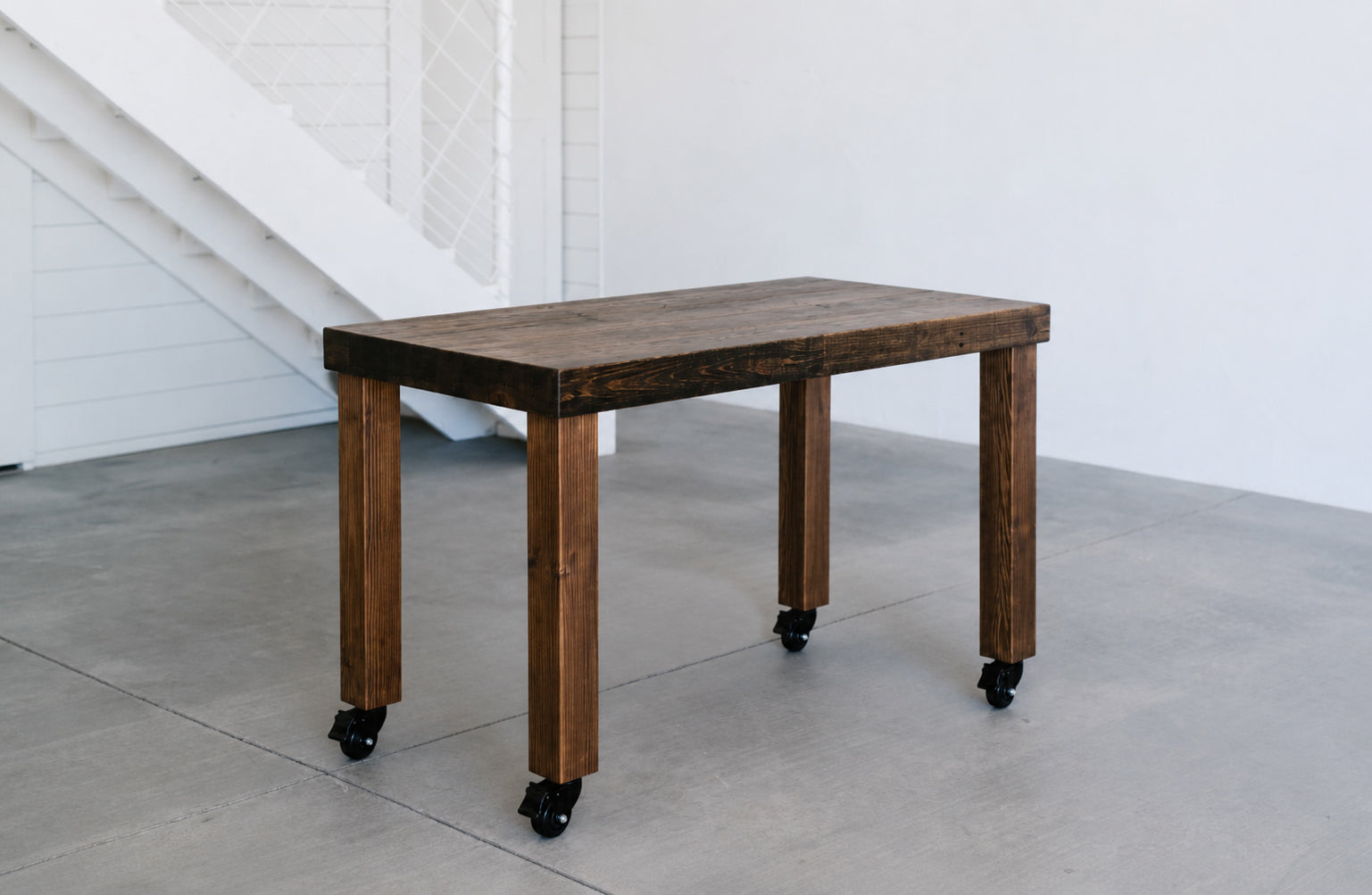 Solid wood desk on caster wheels in a light and bright studio. Handmade by Kase Custom in Arizona and finished in Provincial. 