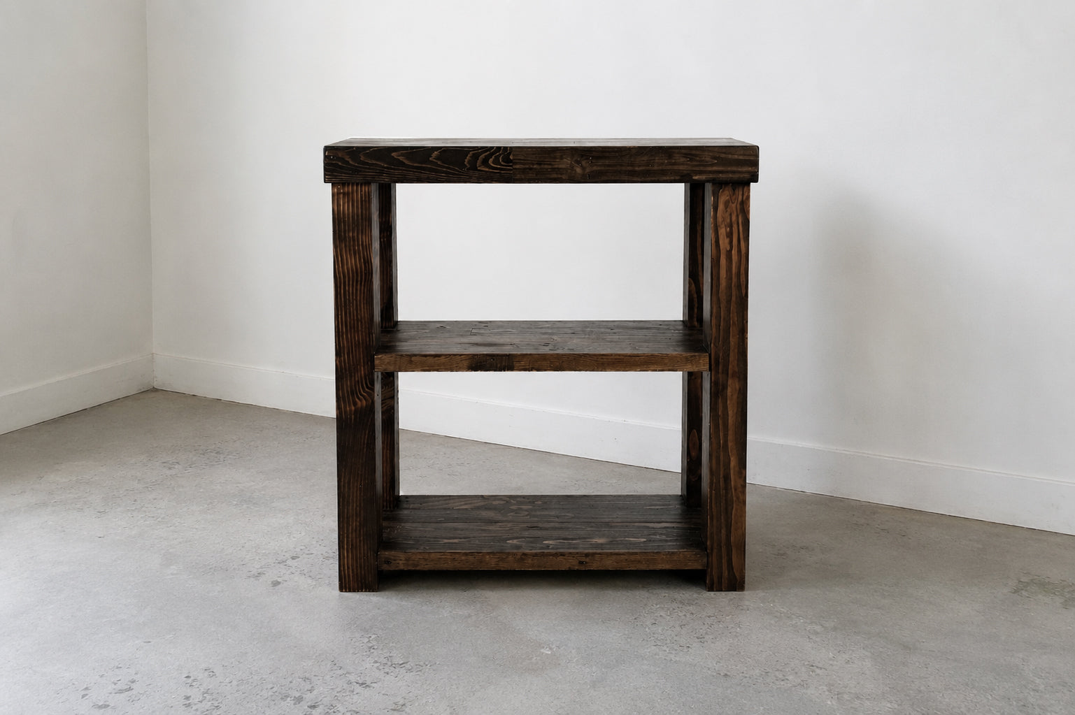 Espresso finish custom solid wood coffee bar on concrete floor in front of white wall. 